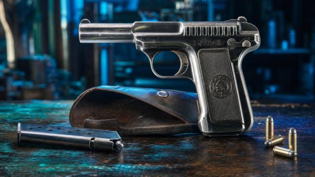 Historicky presná pištoľ Savage Model 1907 na stole v dobovej zbrojárskej dielni.