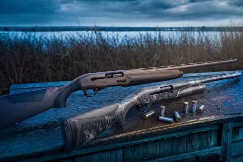 Beretta A400 Xtreme Plus a Benelli Super Black Eagle 3 vedľa seba v poľovníckom kryte pri mokradi.