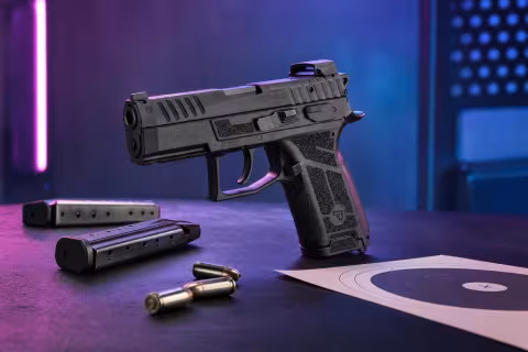 CZ P-09 C Nocturne s kompaktným kolimátorom a dvoma zásobníkmi na streleckom stole.