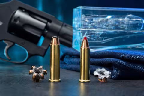 Náboje Speer Gold Dot a Hornady Critical Defense v kalibri .22 WMR vedľa expandovaných striel a krátkeho revolvera.