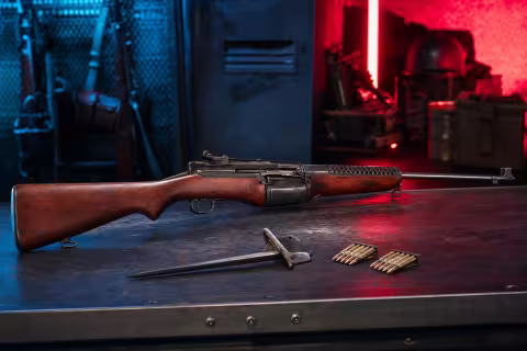 Historicky presná samonabíjacia puška Johnson M1941 na stole dobovej vojenskej dielne.