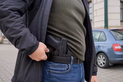 Skryto nosená krátka zbraň v pevnom puzdre pod bundou civilistu.