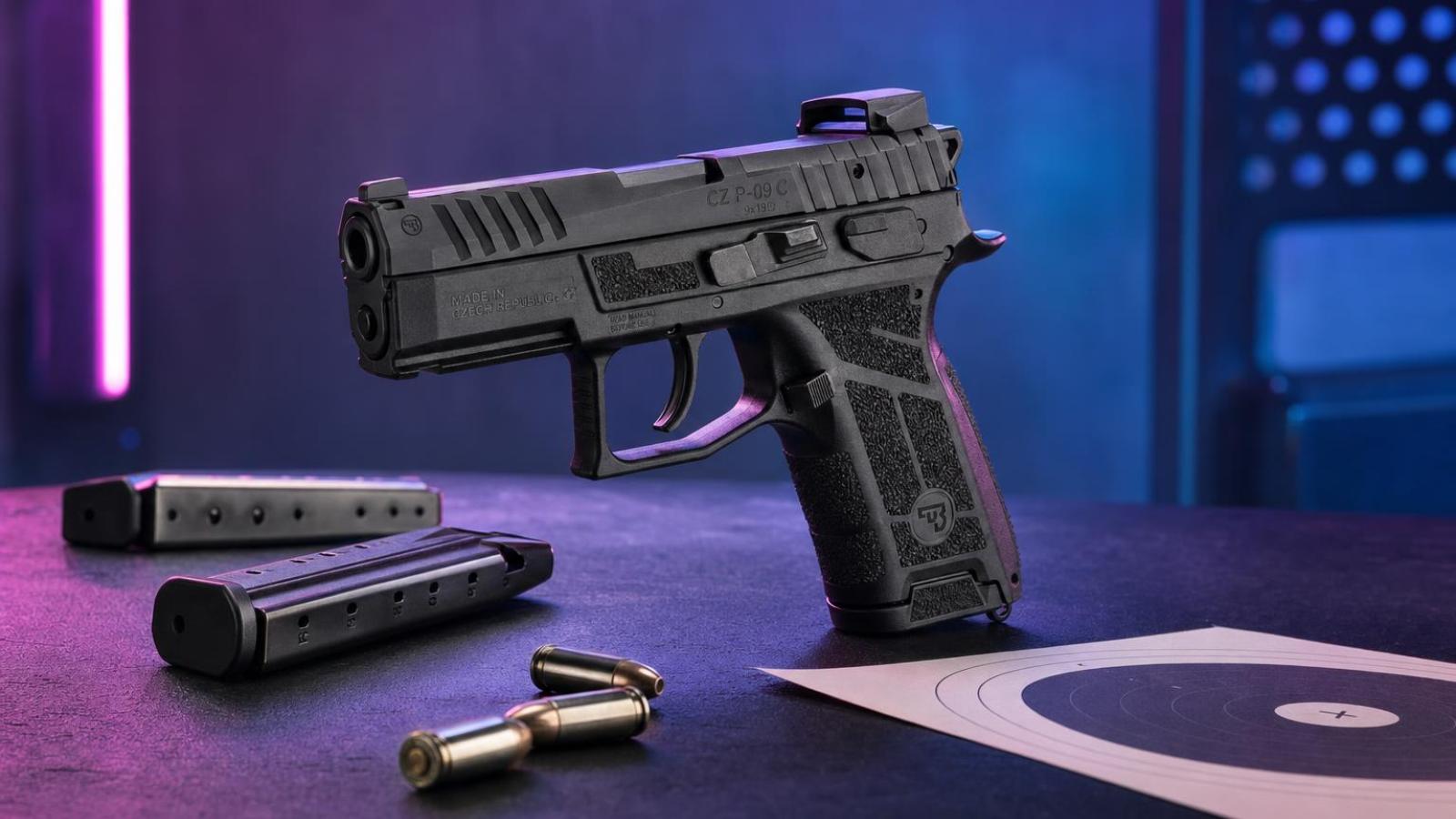 CZ P-09 C Nocturne s kompaktným kolimátorom a dvoma zásobníkmi na streleckom stole.