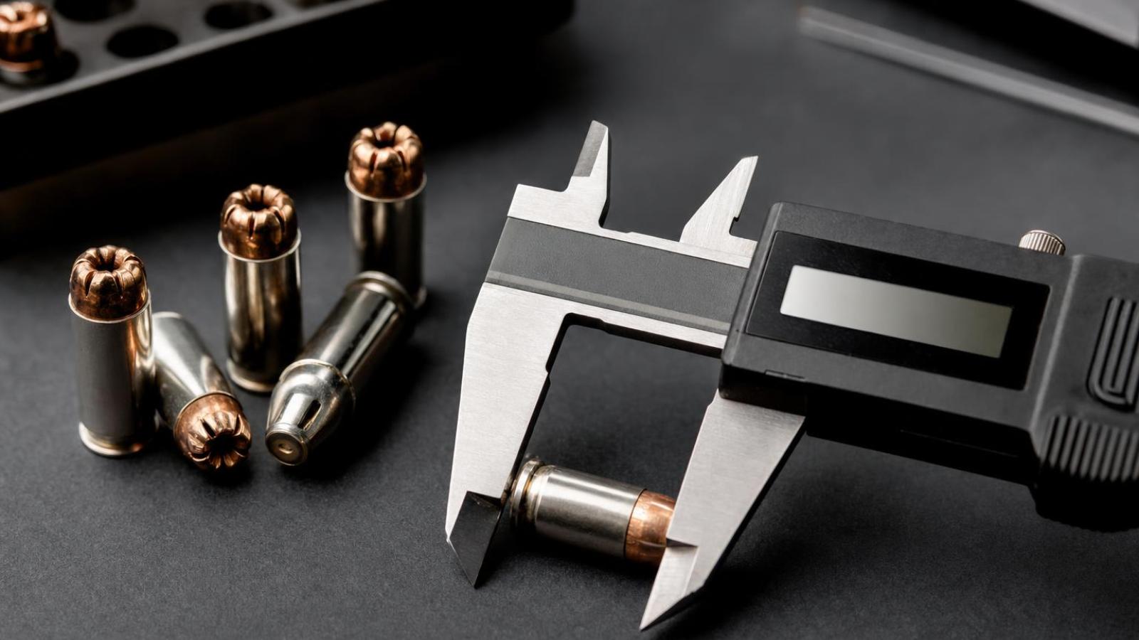 Meranie dĺžky náboja 9 mm posuvným meradlom pri kontrole zatlačenia strely.